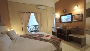 A hotel room with a bed, a desk, a TV, and a balcony. - Samawa Transit Hotel (Sumbawa Besar)