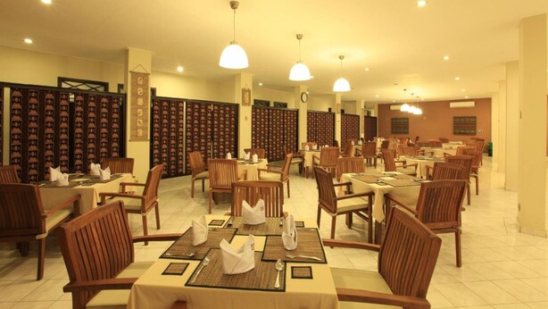 A dining area with multiple tables and chairs, arranged in a spacious layout. - Samawa Transit Hotel (Sumbawa Besar)