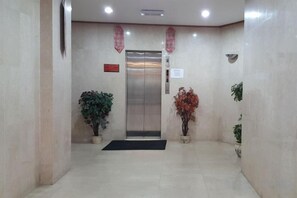A lobby with a reception desk, a reception area, and a staircase leading to an elevator.