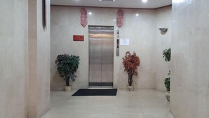 A lobby with a reception desk, an elevator, and potted plants.