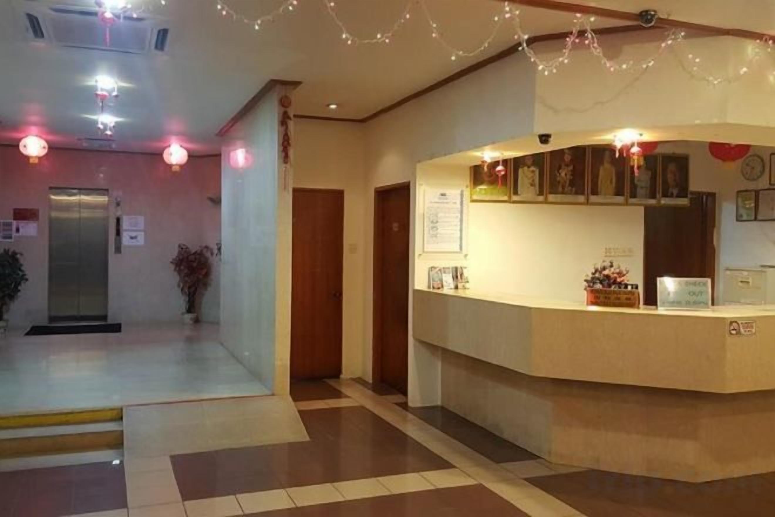 A hotel reception area with a reception desk, a security camera, and a potted plant.