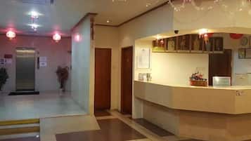 A hotel reception area with a reception desk, a security camera, and a potted plant.