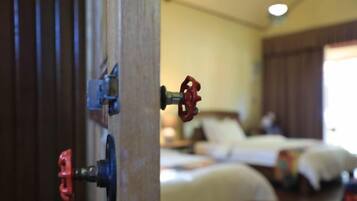 A hotel room with a bed, a nightstand, and a door with a lock.