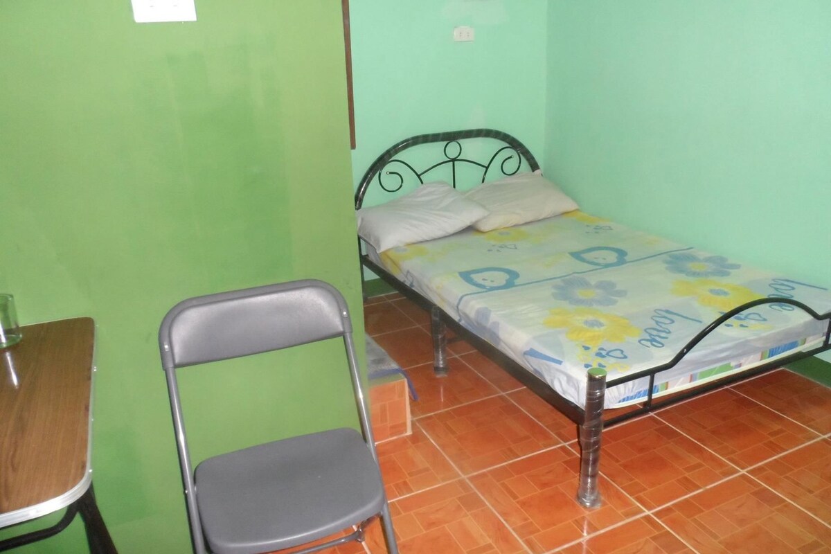 A small room with a single bed, a chair, and a table.