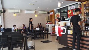 Un interno di un ristorante con tavoli, sedie e un bancone con il menu.