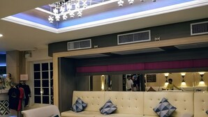 Una hall moderna con un divano beige, un tavolino da caffè in vetro e un'area salotto con poltrone.