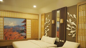 Camera d'albergo con due letti, un grande dipinto del Monte Fuji e decorazioni murali.