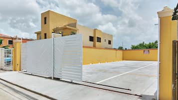 A gated parking area with a yellow building in the background.