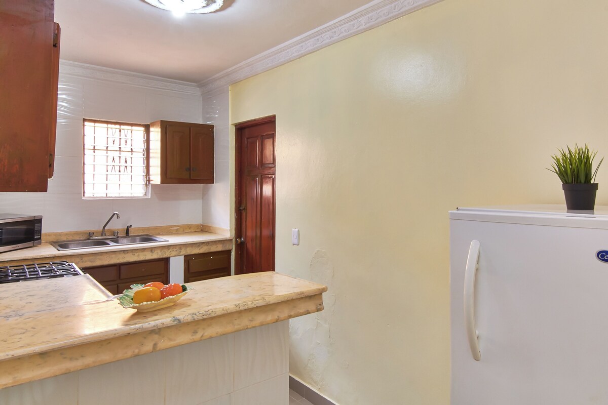 A kitchen with a microwave, sink, and a refrigerator.