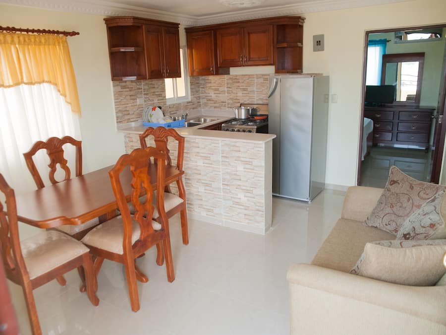 Uma cozinha compacta com armários de madeira, uma ilha integrada e uma geladeira.