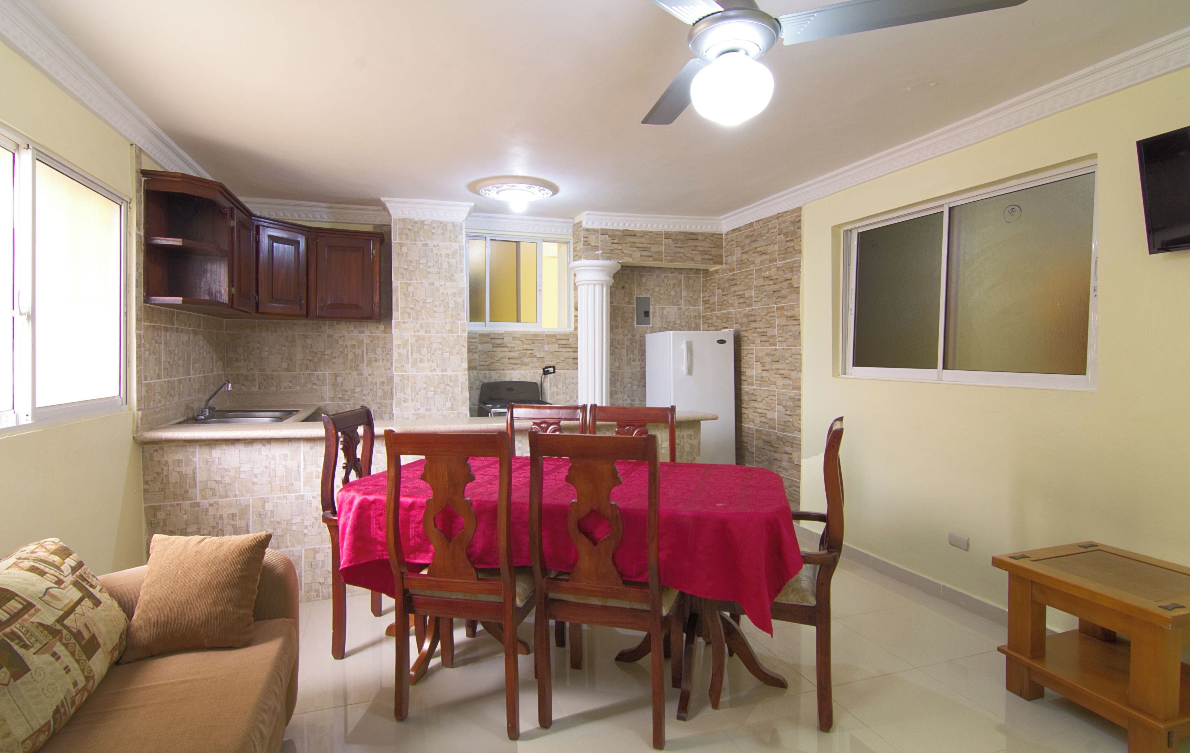 A compact kitchen with a dining area, a refrigerator, and a ceiling fan.
