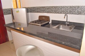A compact kitchen with a gas stove, a sink, and a refrigerator. - Tropical Island Aparthotel (Santo Domingo Este)