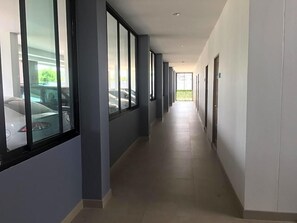 Un long couloir étroit, avec de grandes fenêtres d’un côté, qui mène à un espace de stationnement.