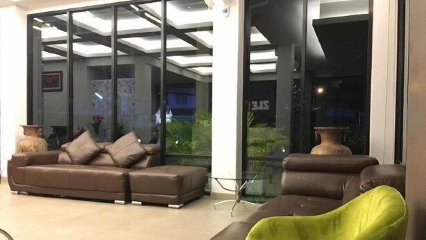 A modern living room with a brown sofa, a green armchair, and a glass coffee table. - Zleep D Hotel (Udon Thani)