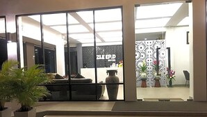 A hotel lobby with a reception desk, seating area, and decorative plants. - Zleep D Hotel (Udon Thani)
