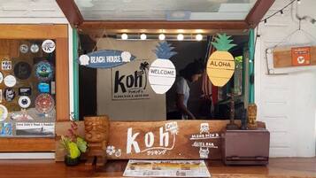 Een kiosk in strandthema met een houten toonbank, een 'Welcome'-bord en diverse decoratieve objecten.