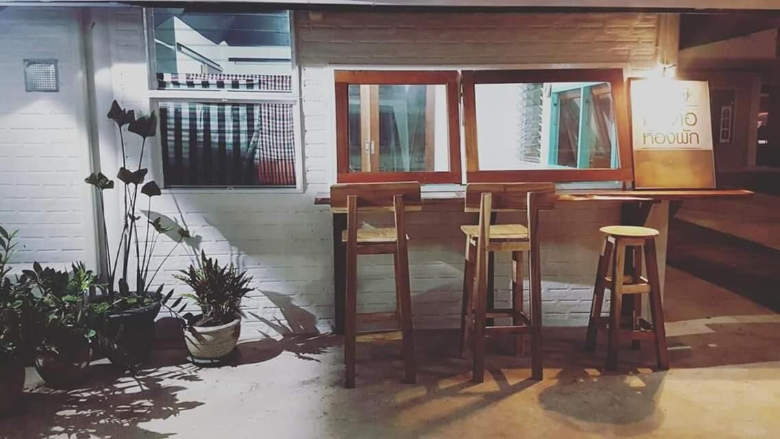 Een gezellig buiten zitgedeelte met houten tafels en stoelen, omringd door plantenpotten.