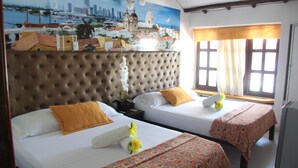 A hotel room with two beds, a large cityscape mural, a window with curtains, and a view of the city.