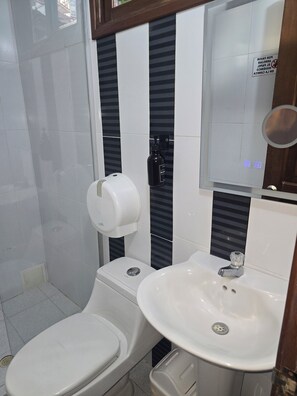 A bathroom with a toilet, a hand dryer, and a sink with a mirror above it. - Rodadero Dorado (Santa Marta)