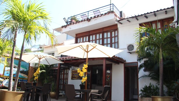 An outdoor seating area with tables and chairs, umbrellas, and potted plants.