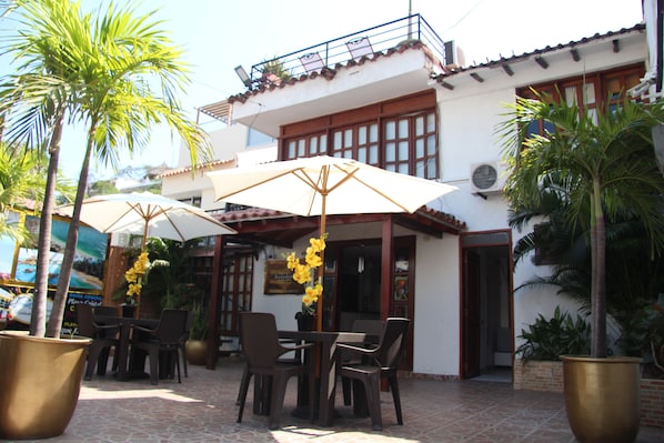 An outdoor seating area with tables and chairs, umbrellas, and potted plants. - Rodadero Dorado (Santa Marta)