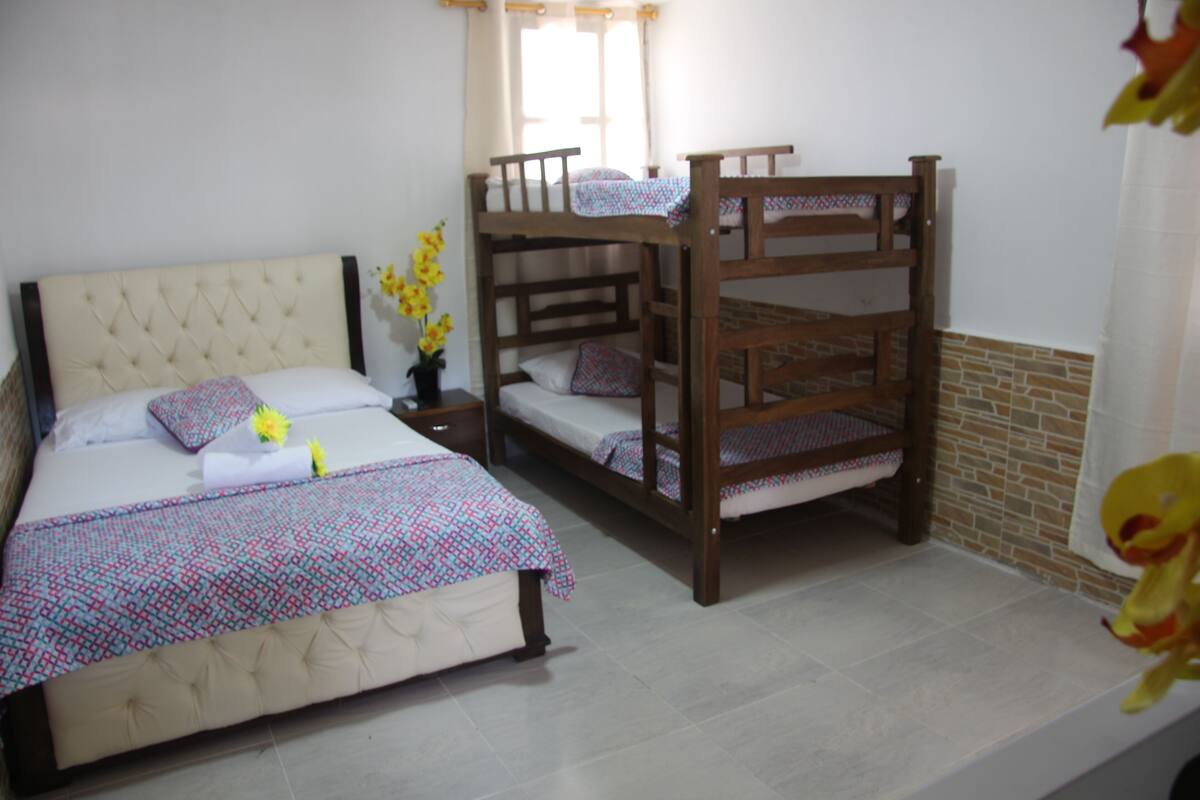 A bedroom with a single bed, a bunk bed, a nightstand, and a window with curtains.