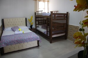 Un dormitorio con una cama litera y una cama individual, ambas con ropa de cama estampada.