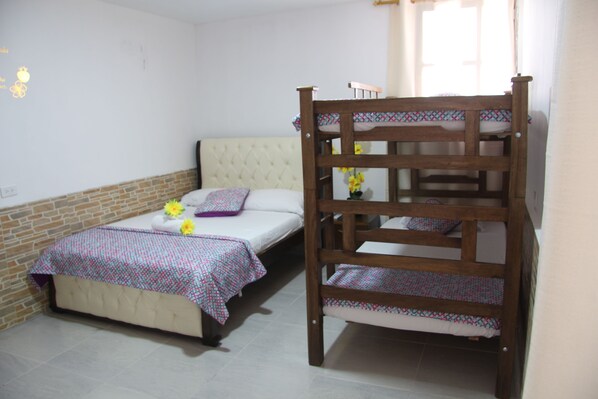 A room with a bunk bed, a single bed, and a brick accent wall.