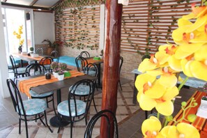 A restaurant with multiple tables and chairs, a brick wall with greenery, and a wooden column. - Rodadero Dorado (Santa Marta)
