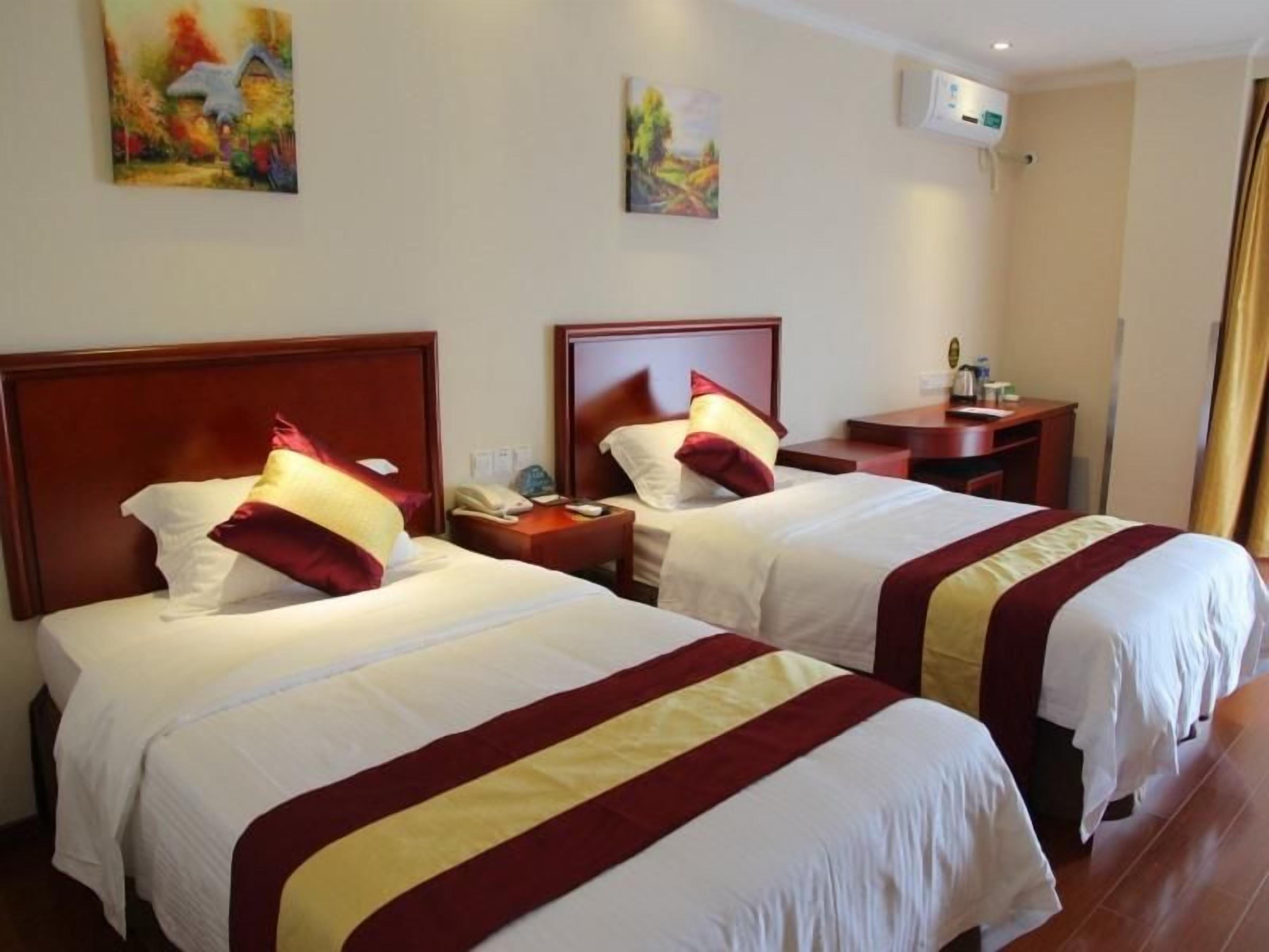Quarto de hotel com duas camas, mesa de cabeceira e ar-condicionado fixado na parede.