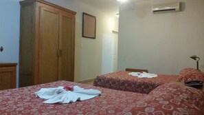A hotel room with two beds, a wardrobe, an air conditioning unit, and a framed picture on the wall. - New Garden Hotel (Sosúa)