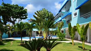 A hotel with a pool, palm trees, and a blue building.