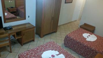 Ein Hotelzimmer mit zwei Betten, einem Holztisch, einem Kleiderschrank und einem Spiegel.