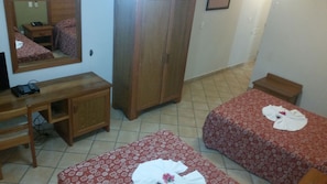 A hotel room with two beds, a wooden desk, a wardrobe, and a mirror.