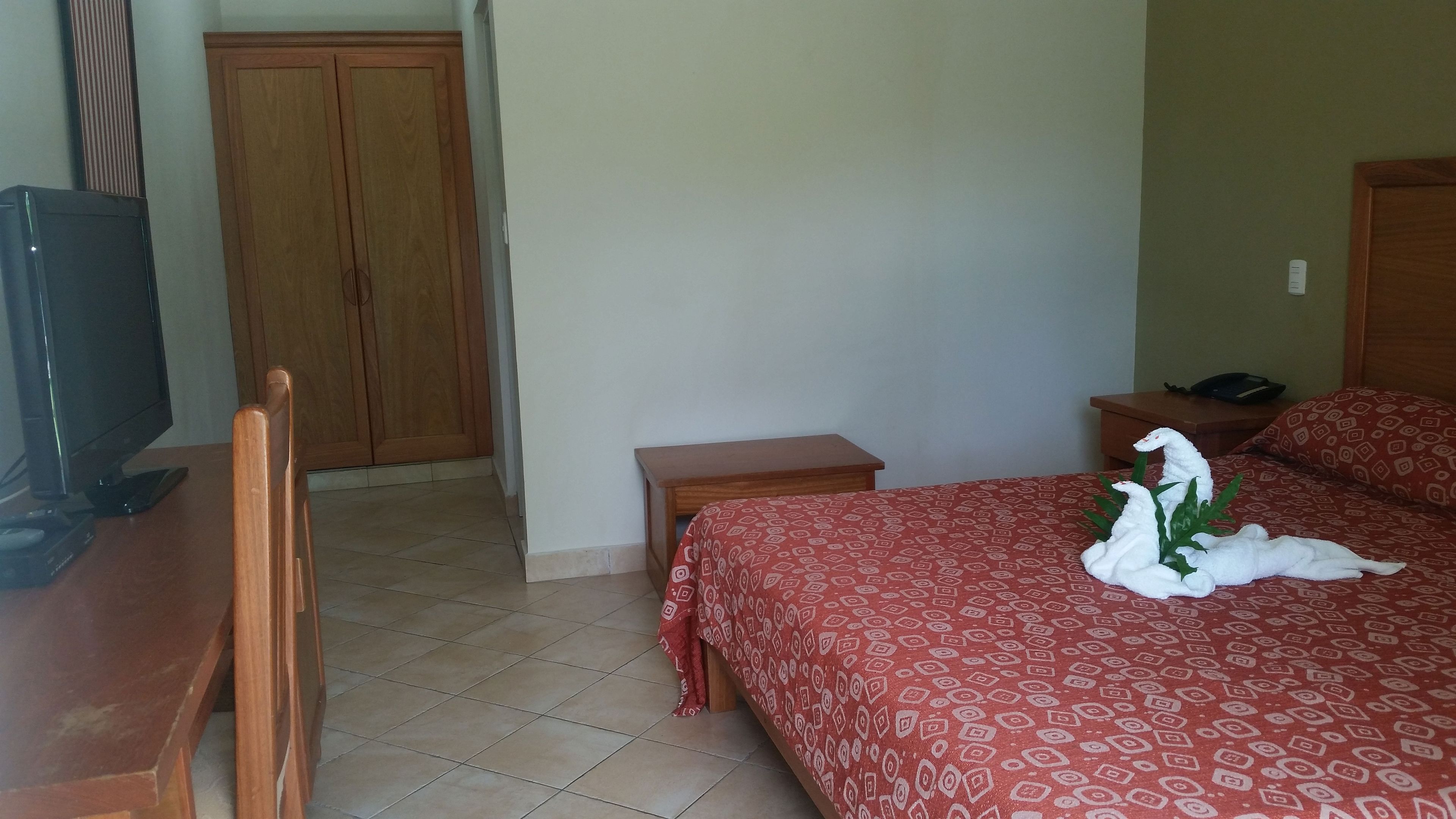 A hotel room with a bed, a desk, a television, and a wardrobe.