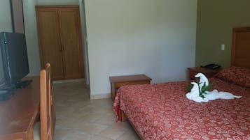 A hotel room with a bed, a desk, a television, and a wardrobe.