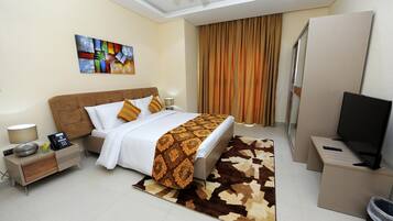 Una habitación de hotel con cama, mesita de noche, lámpara y televisión.
