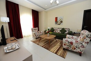 A living room with a sofa, two armchairs, a coffee table, and a TV. - Al Mansour Park Inn Hotel Apartment (Doha)