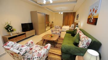Una sala de estar con un sofá, una mesa de centro, un televisor y un arreglo floral.