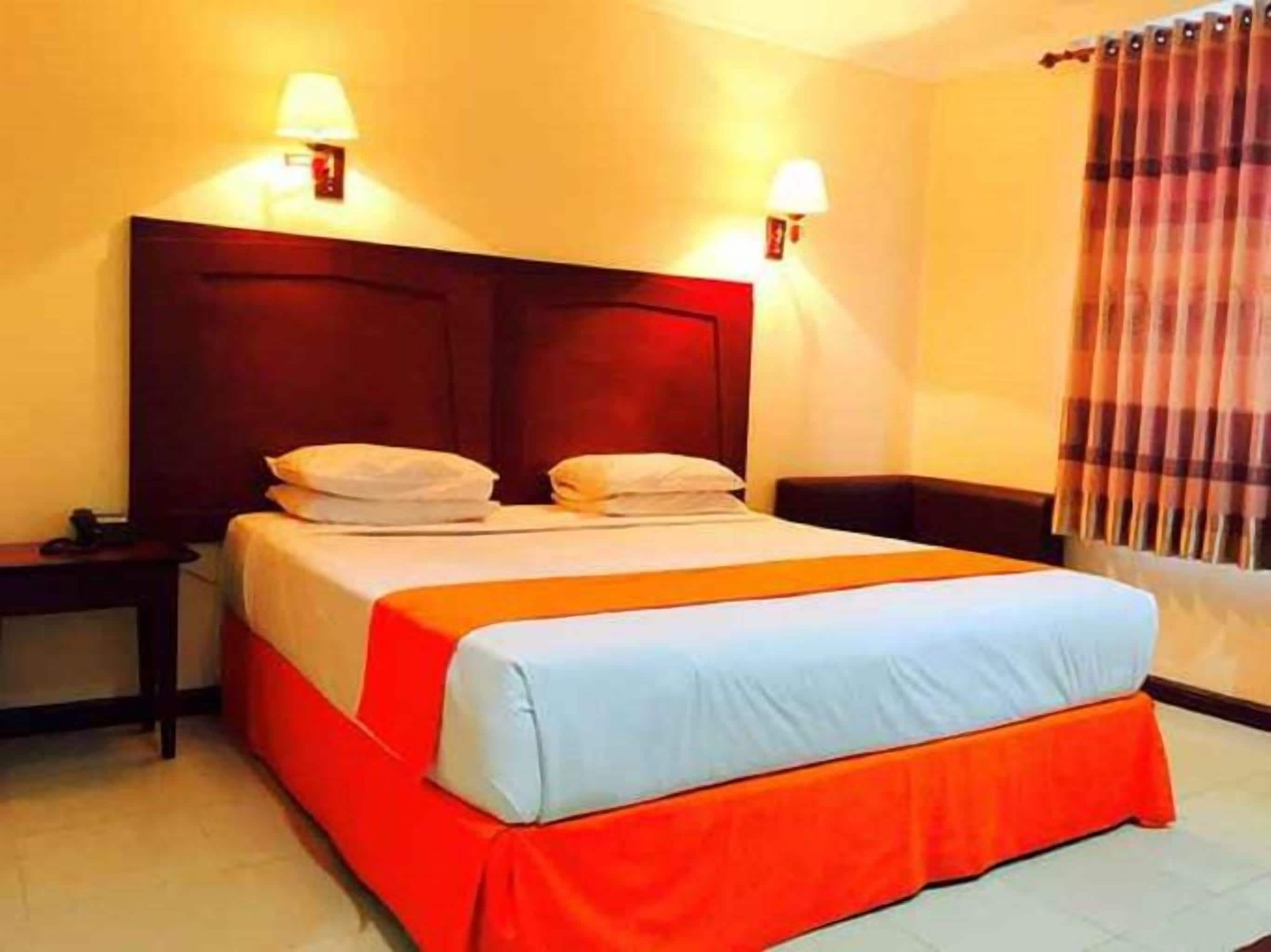 A hotel room with a bed, nightstands, and wall-mounted lamps.
