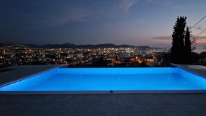 Una piscina amb vistes a un paisatge urbà a l'hora del vespre.