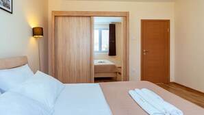A hotel room with a bed, a bathroom visible through an open door, and a towel on the bed. - Uphill Glavanovic Villa (Bar)
