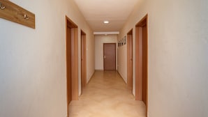 A hallway with wooden doors, a tiled floor, and a wooden coat rack. - Uphill Glavanovic Villa (Bar)