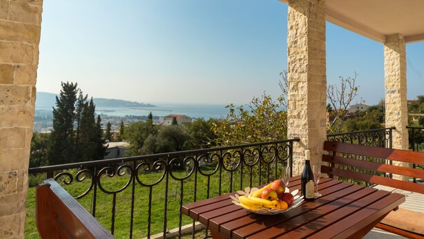 A balcony with a wooden table, a metal railing, and a bench. - Uphill Glavanovic Villa (Bar)