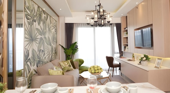 A modern living room with a sofa, dining table, and a kitchen area with a TV.