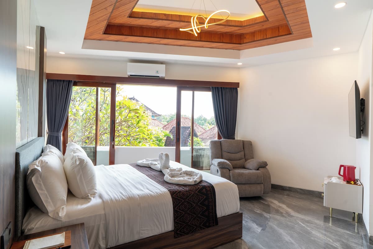 Une chambre d’hôtel moderne, dotée d’un grand lit, d’un canapé, d’une télévision et offrant une vue sur la verdure environnante.