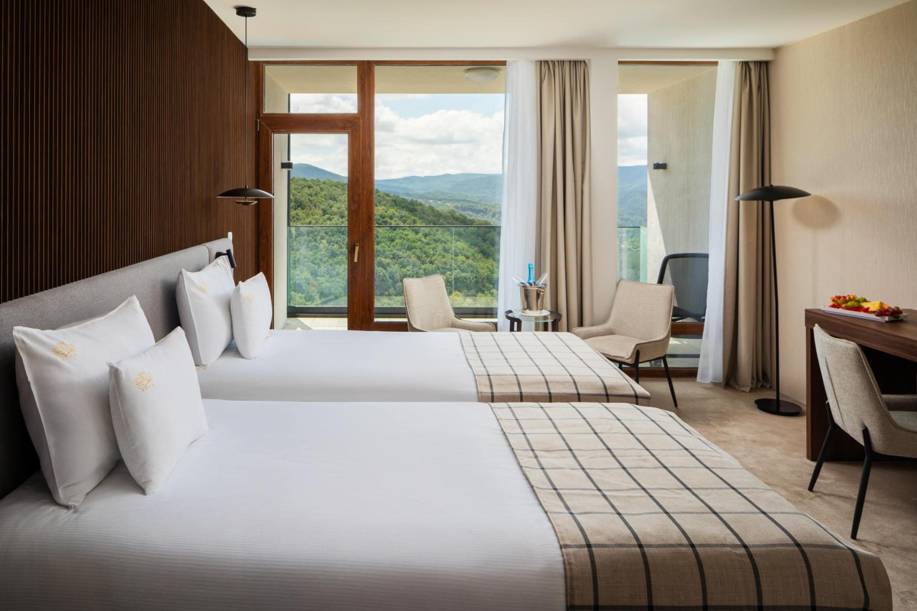 Habitación de hotel con dos camas, un escritorio, una silla y vistas a las montañas.
