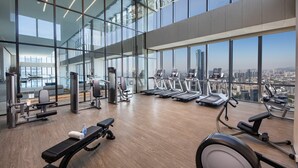 A modern gym with various exercise equipment, large windows, and a city view. - Crowne Plaza Shenzhen Nanshan (Shenzhen)