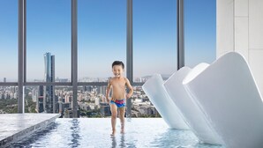 A child in a swimming pool with a cityscape view through large windows. - Crowne Plaza Shenzhen Nanshan (Shenzhen)