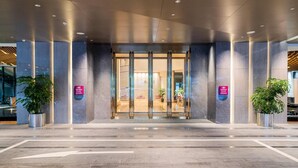 A modern hotel entrance with glass doors, potted plants, and a sign indicating the hotel's name. - Crowne Plaza Shenzhen Nanshan (Shenzhen)